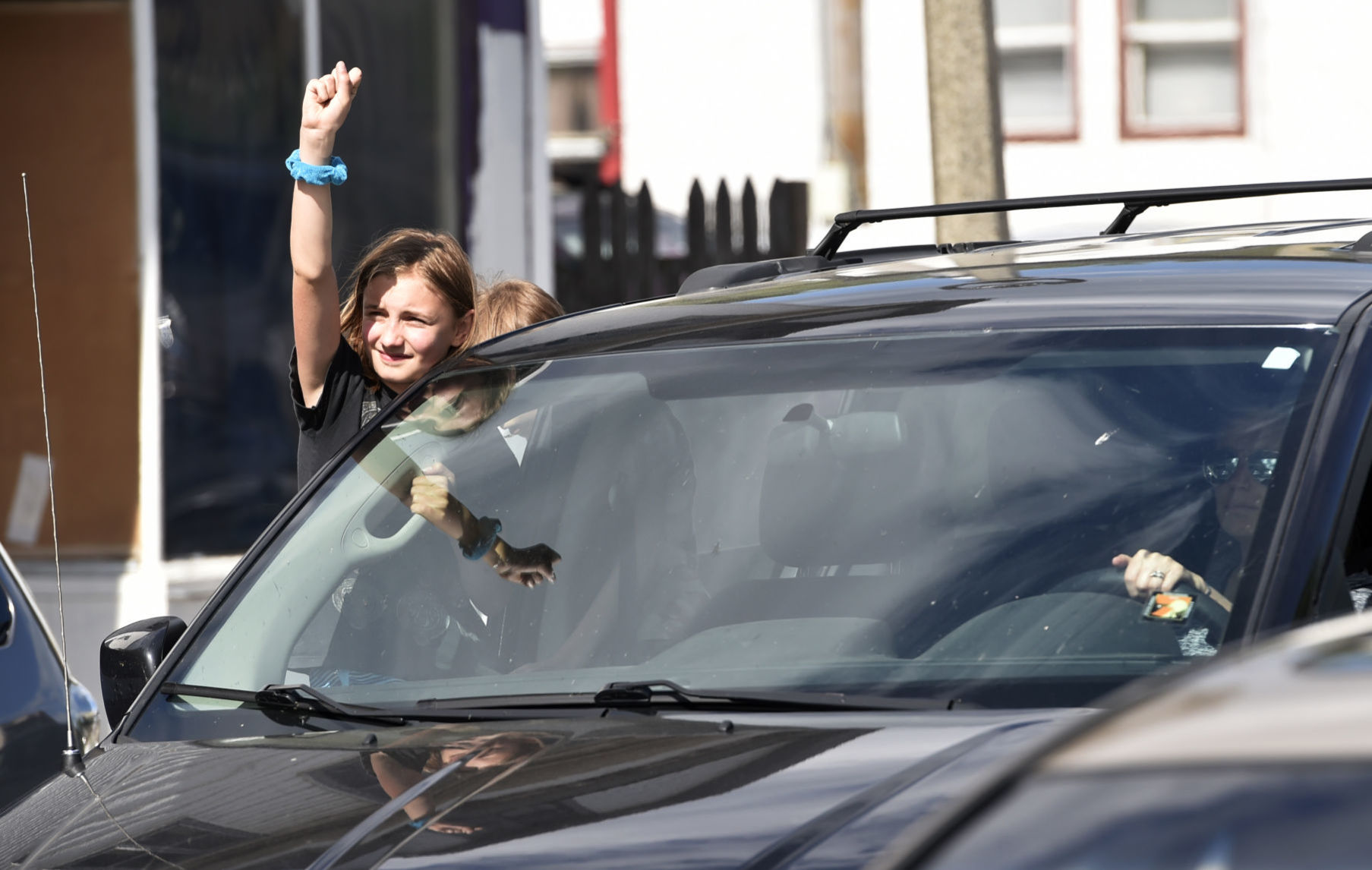 Young girl with her fist in the air outside of a minivan